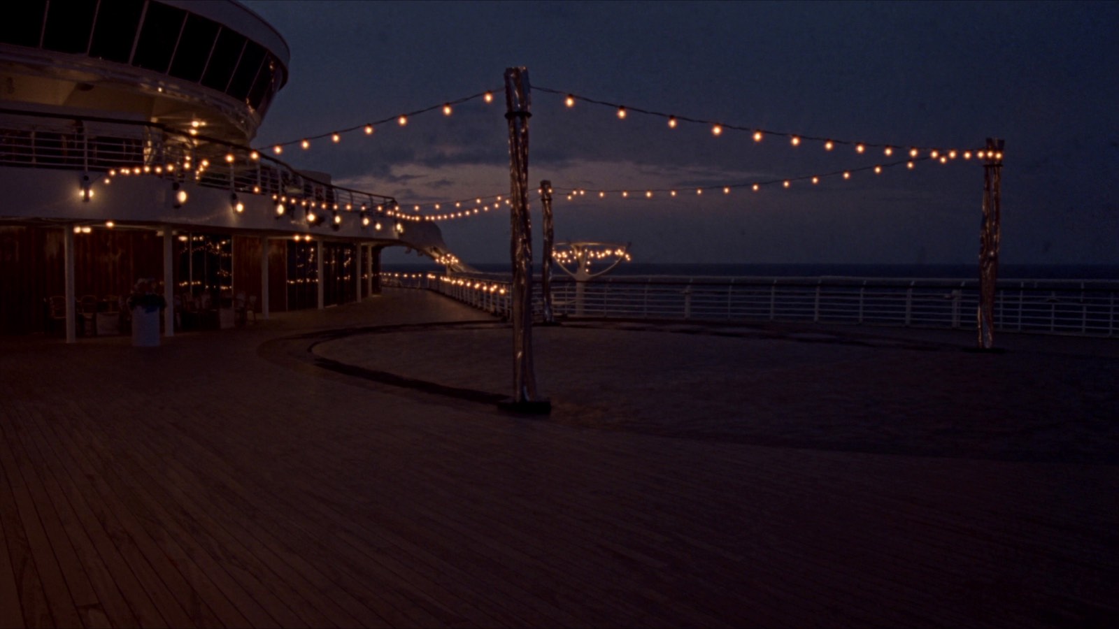 An empty upper deck strung with lights at dusk