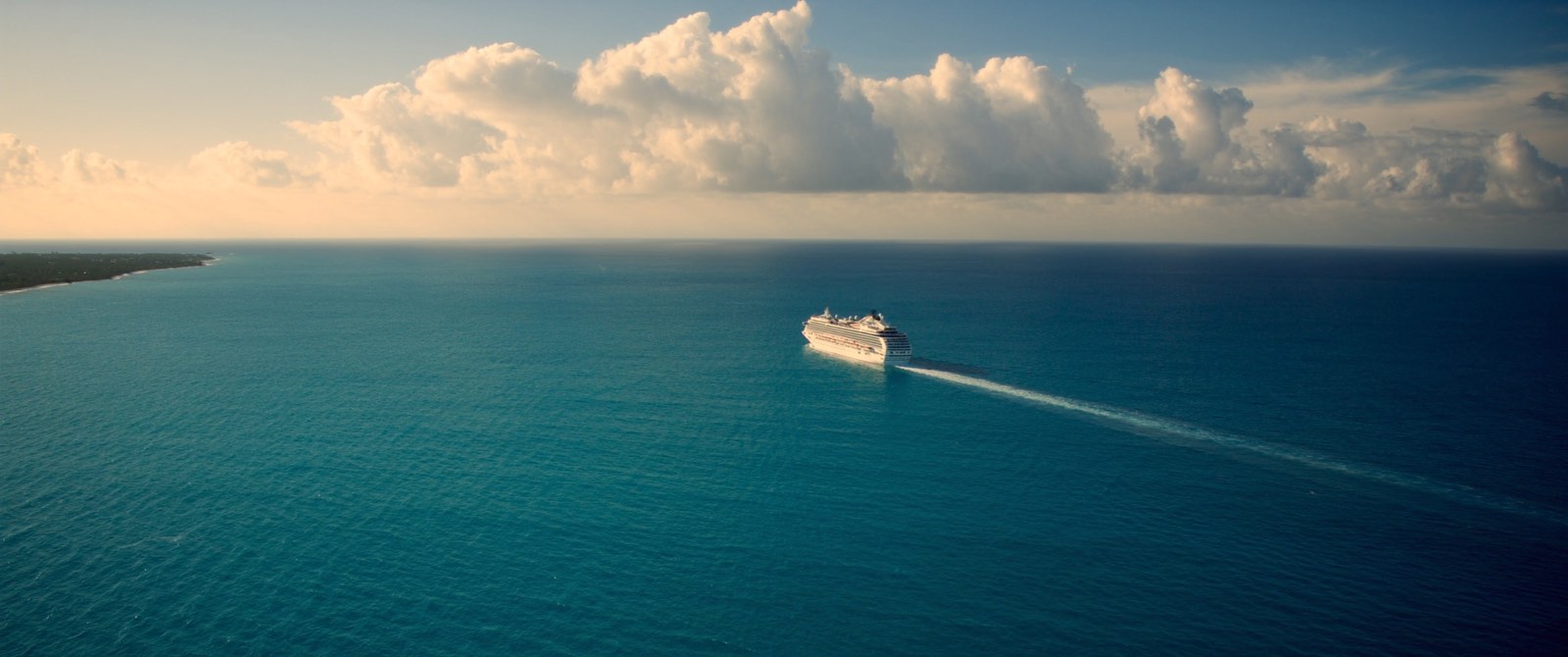 A cruise ship crossing open Caribbean water in late afternoon light